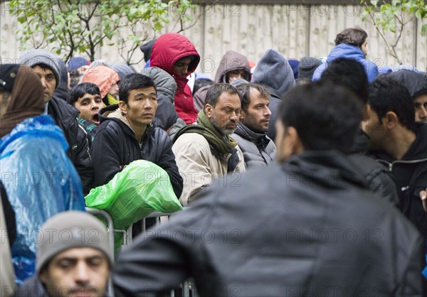 Syrian refugees wait for their registration in cold and wet weather at the Berlin State Office for