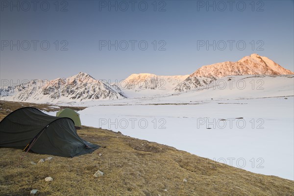 Icy tents in expedition camp at sunrise over the mountain peaks in the snow-covered Tavan Bogd