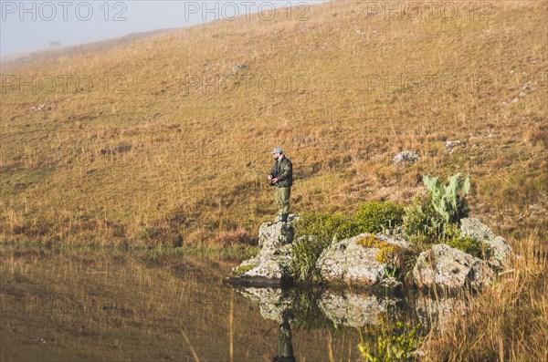 Sport fisherman fishing in lake on cloudy day, Cambara do sul, Rio Grande do sul, Brazil, South