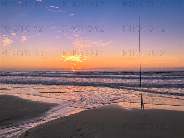 Fishing rod on beach at sunset, surfing cast