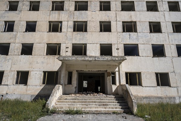 Entrance to an abandoned ruined residential building, old Soviet apartment block in the ghost town,