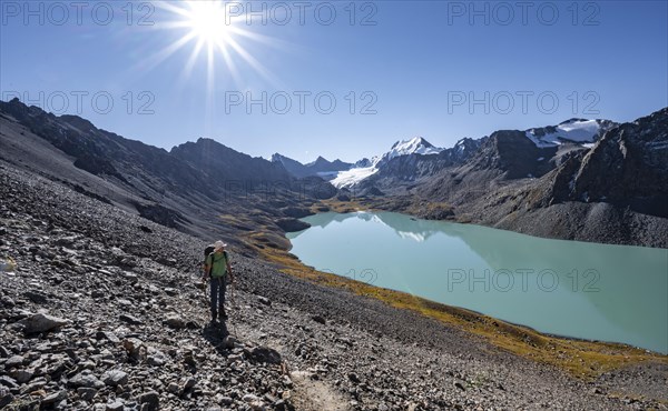 Mountaineers on the way to the Ala Kul Pass, turquoise Ala Kul mountain lake in the morning light,