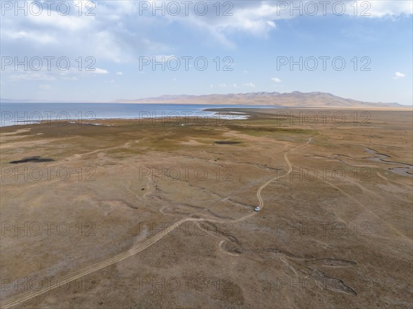 Road and off-road vehicle, Aerial view, Vast empty landscape at the mountain lake Song Kul in