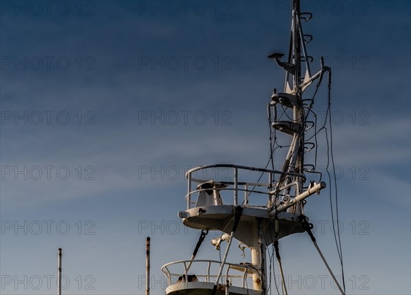 Closeup of rusted crows nest section of an old ship with a blue sky in the background in NamHae,