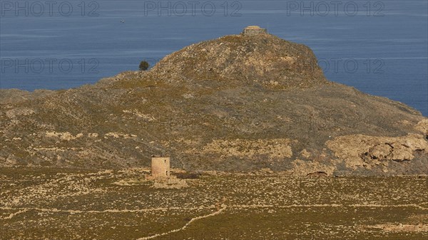 Ruins of a windmill, Hilly landscape with historical ruins and a path through the grass, Lindos,