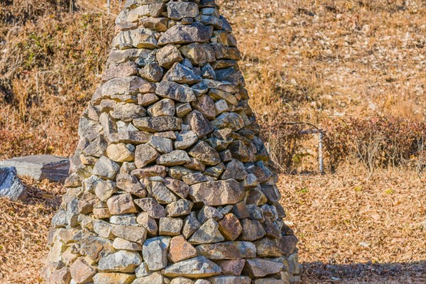 Closeup of pile of stones in the shape of an upside down cone in a public road side park near