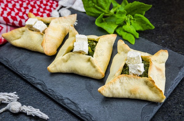Delicious Lebanese (Arabic) food, spinach sfiha with ricotta cheese on a black slate stone