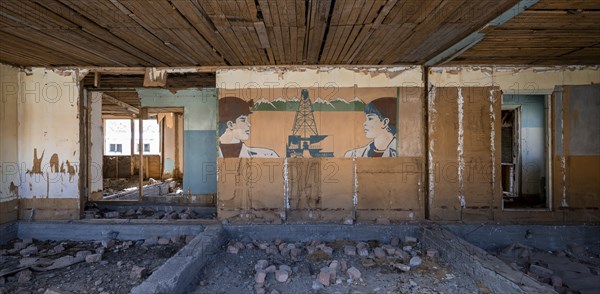 Destroyed abandoned classroom of the old school, wall painting with Soviet miners, ghost town,
