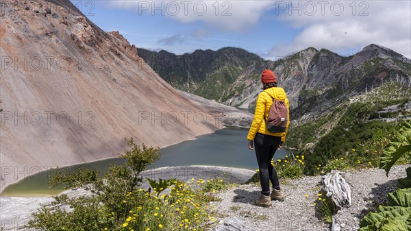 Young woman in yellow jacket standing in front of a volcano, Chaiten Volcano, Carretara Austral,