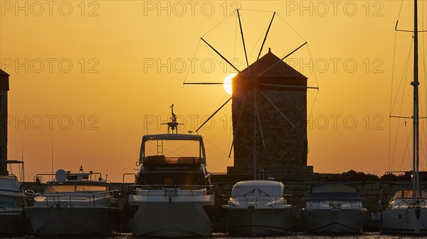 Windmill and boats silhouetted against a sunrise backdrop, twilight, Mandraki Oat, Rhodes,