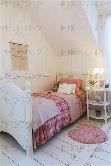 Single bed with red, pink and grey tartan bedspread, white painted antique style wooden headboard
