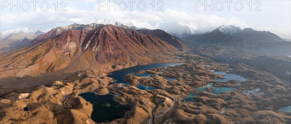Atmospheric aerial view, high mountain landscape with glacier moraines and mountain lakes, behind