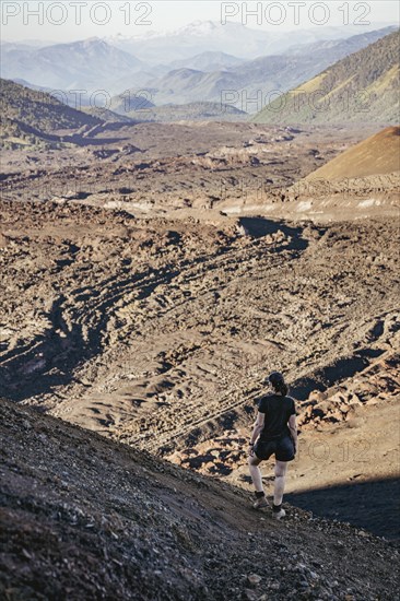 Young woman looking at lava fields, Crater Navidad, Lonquimay volcano, Malalcahuello National