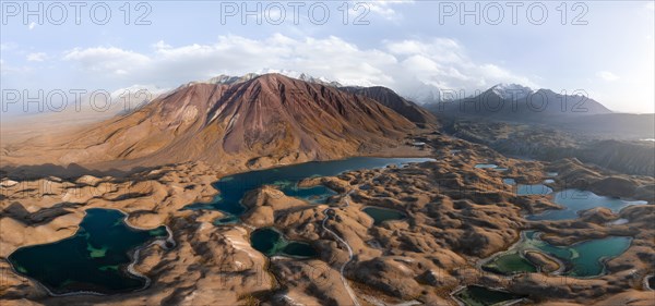 Atmospheric aerial view, high mountain landscape with glacier moraines and mountain lakes, behind