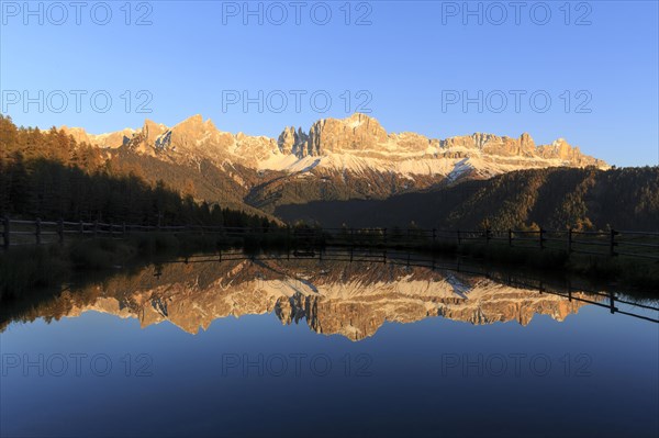 The last rays of the day illuminate the mountains reflected in a calm lake, Trentino-Alto Adige,