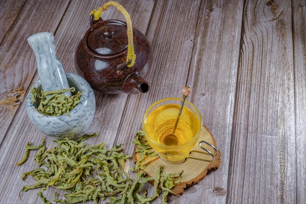 Lemon verbena infusion in a glass cup with a marble mortar and pestle and a ceramic teapot with