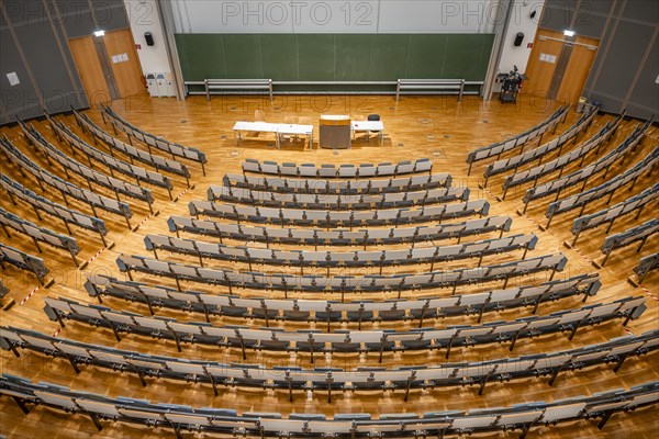 View from above into an empty lecture theatre with rows of seats and lectern, interior photo,