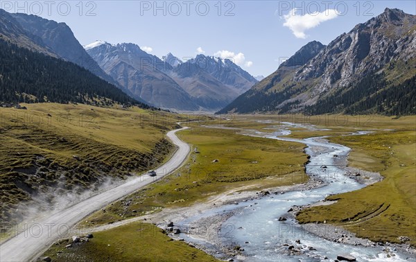 Car on road, mountain river in green mountain valley in the Tien Shan Mountains, Jety Oguz,