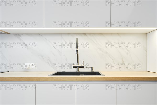 Water tap and sink in a modern bright kitchen