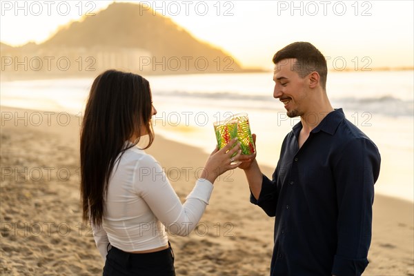 Side view of a romantic newlywed couple toasting during sunset on the beach