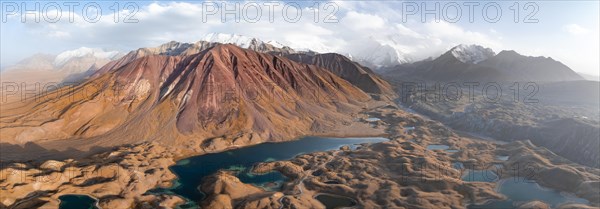 Atmospheric aerial view, high mountain landscape with glacier moraines and mountain lakes, behind