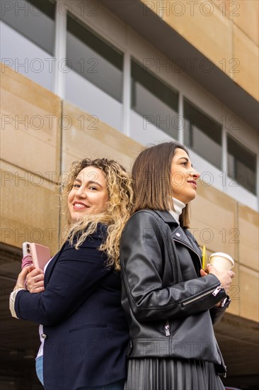 Portrait of two female entrepreneurs with crossed arms outside a building. Portrait of two business