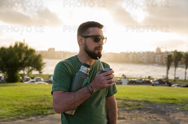 Man drinking chimarrao, mate tea tea (an infusion of yerba mate tea tea with hot water) at sunset