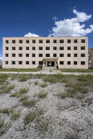 Abandoned destroyed residential building, old Soviet block of flats in the ghost town, Engilchek,