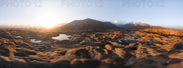 Atmospheric aerial view, high mountain landscape with glacier moraines and mountain lakes, behind
