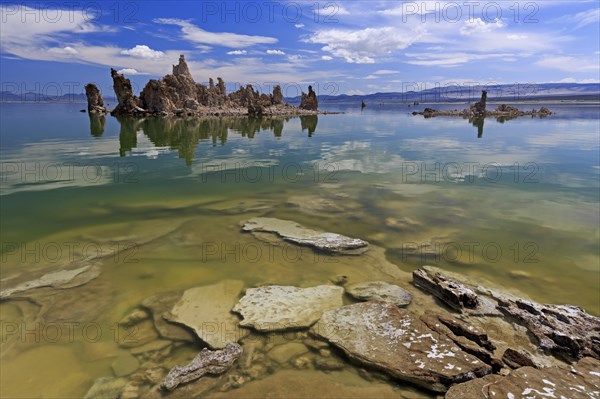 Limestone tufa structures protrude into a lake with clear water and a cloudy sky, Mono Lake, North