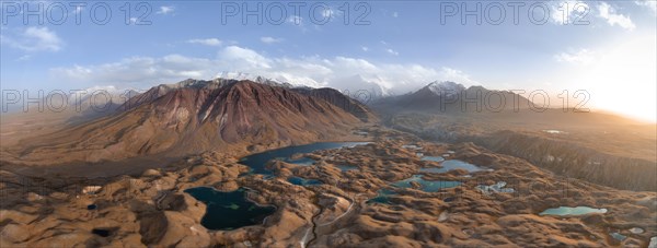 Atmospheric aerial view, high mountain landscape with glacier moraines and mountain lakes, behind