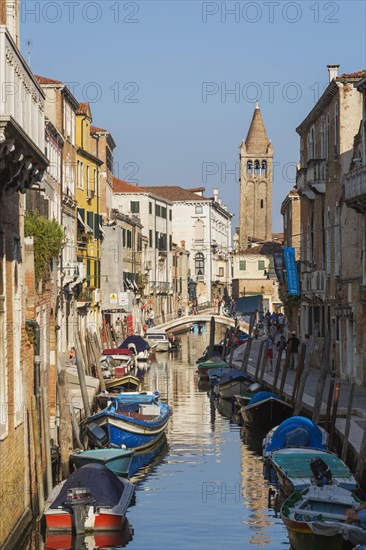 Moored boats on San Barnaba canal with footbridge and old architectural style residential buildings