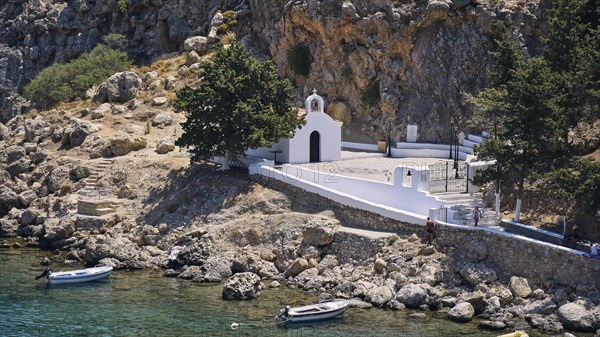 A white church on the Mediterranean Sea on a rocky shore next to parked boats, St Paul's Chapel,