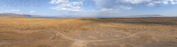 Road and off-road vehicle, Aerial view, Vast empty landscape at the mountain lake Song Kul in