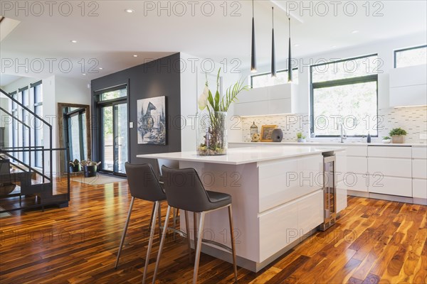 White high-gloss lacquered cabinets and island with grey leather bar stools and white quartz