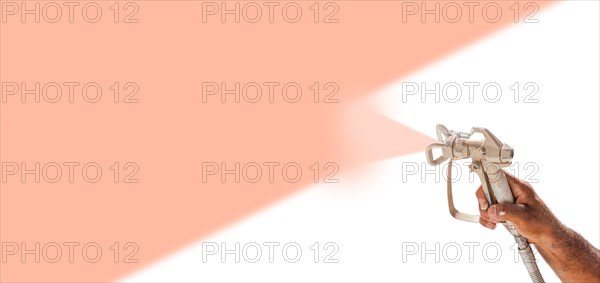 Professional spray painter holding spray gun spraying peach fuzz PMS color of the year 2024 over