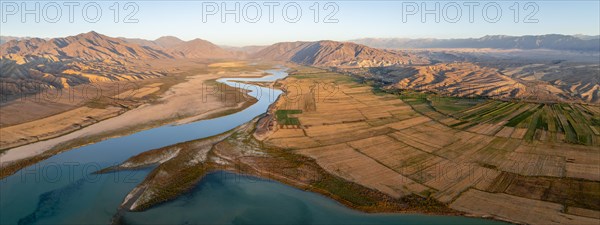 Naryn River between mountains and fields, at Toktogul Reservoir at sunset, aerial view, Kyrgyzstan,