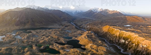Atmospheric aerial view, high mountain landscape with glacier moraines and mountain lakes, behind