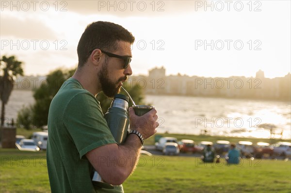 Man drinking chimarrao, mate tea tea (an infusion of yerba mate tea tea with hot water) at sunset
