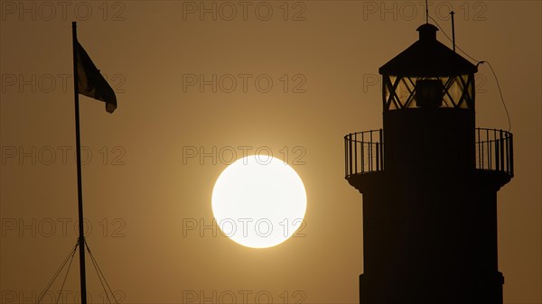 Silhouette of a lighthouse in front of an Orange coloured sky at sunrise, sunrise, dawn, Fort of