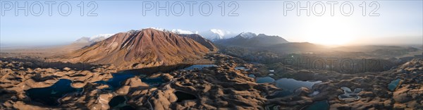 Atmospheric aerial view, high mountain landscape with glacier moraines and mountain lakes, behind