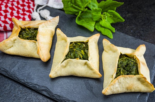 Delicious Lebanese (Arabic) food, spinach sfiha on black slate stone background and traditional