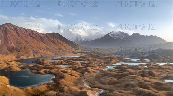 Atmospheric aerial view, high mountain landscape with glacier moraines and mountain lakes, behind