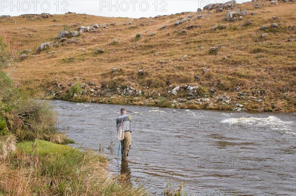 Fisherman fly fishing rainbow trout on mountain in beautiful scenery