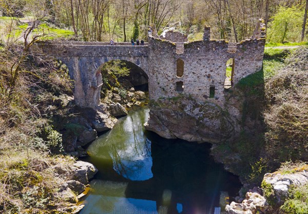 Partially destroyed old stone bridge over a river, surrounded by lush greenery, Bridge of the