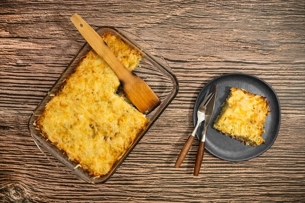 Top view of pie with meat and potato baked in oven in glass baking tray and on a plate