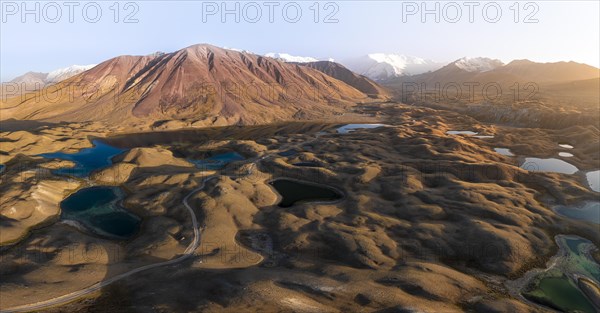 Atmospheric aerial view, high mountain landscape with glacier moraines and mountain lakes, behind