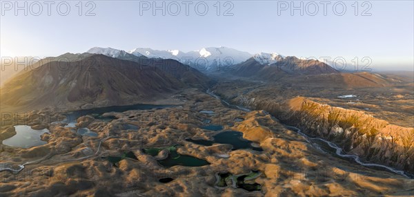 Atmospheric aerial view, high mountain landscape with glacier moraines and mountain lakes, behind