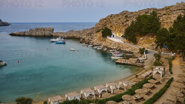Bay with sun loungers and clear water, St Paul's Chapel, Paul's Bay, below the Acropolis of Lindos,