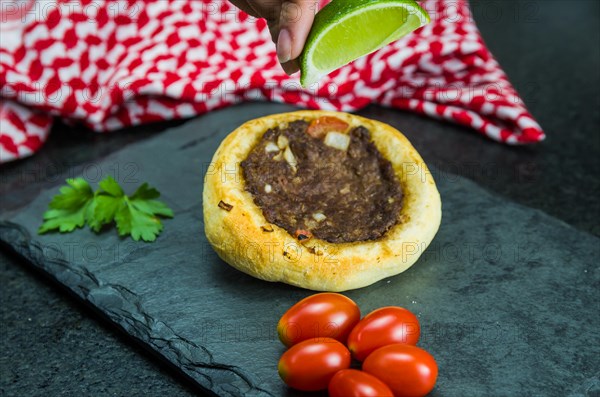 Delicious Lebanese (Arabic) food, squeezing lemon into legitimate sfihas on a black granite